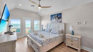 A bedroom with a bed, a TV, a ceiling fan, and a view of the ocean. - Blue Anchor 5 Bedroom Home (Port Bolivar)