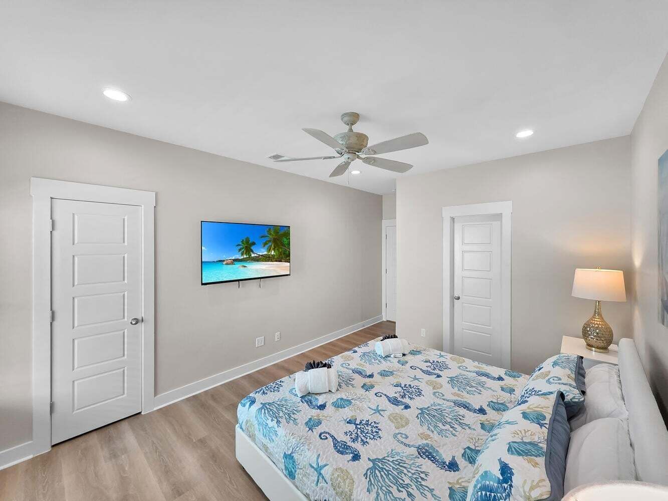Une chambre à coucher avec un lit, un ventilateur de plafond, une télévision et une lampe.