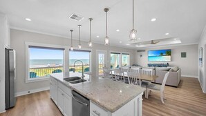 A modern kitchen with a large island, white cabinetry, and pendant lighting. - Blue Anchor 5 Bedroom Home (Port Bolivar)
