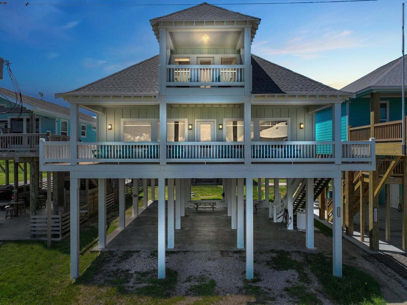 A two-story waterfront house with a balcony, a covered porch, and a staircase leading to the upper level.