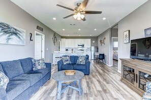 A living room with a sofa, coffee table, and TV stand. - Second Wind 3 Bedroom Home (Port Bolivar)