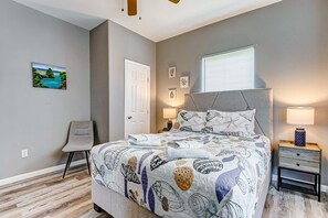 Une chambre à coucher avec un lit, une chaise, une table de chevet, une lampe et un tableau au mur.