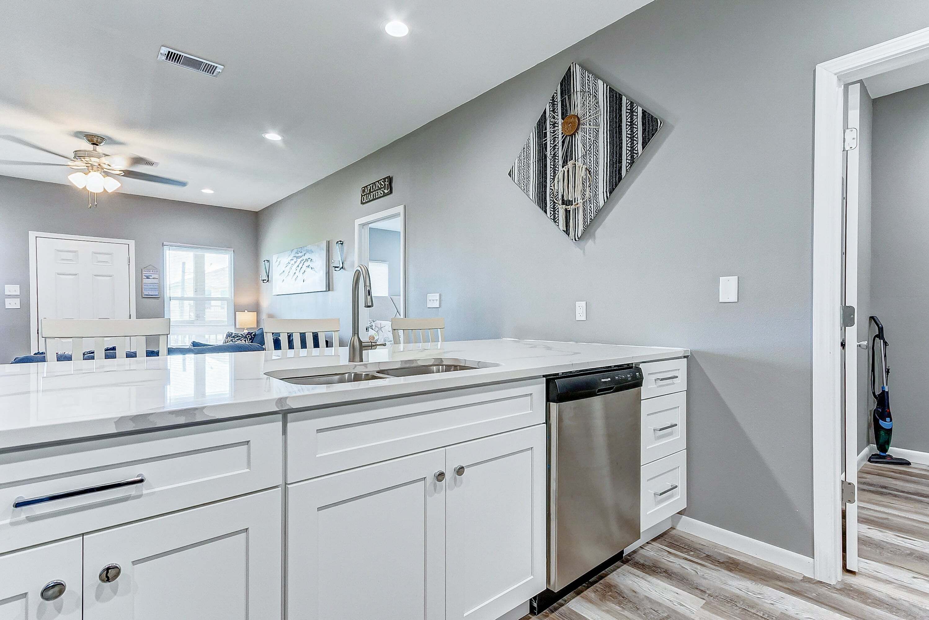 A modern kitchen with white cabinetry, a dishwasher, and a ceiling fan.