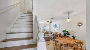 Un escalier menant à un espace de vie comprenant un canapé, une table à manger et des objets de décoration.