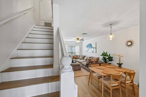 A staircase leading to a living area with a sofa, dining table, and decorative items. - New To Market- Quiet Lakeview Townhome- Pool, Tennis, and Comfort (Bradenton)
