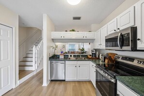 A kitchen with white cabinets, a microwave, a stove, and a dishwasher. - New To Market- Quiet Lakeview Townhome- Pool, Tennis, and Comfort (Bradenton)