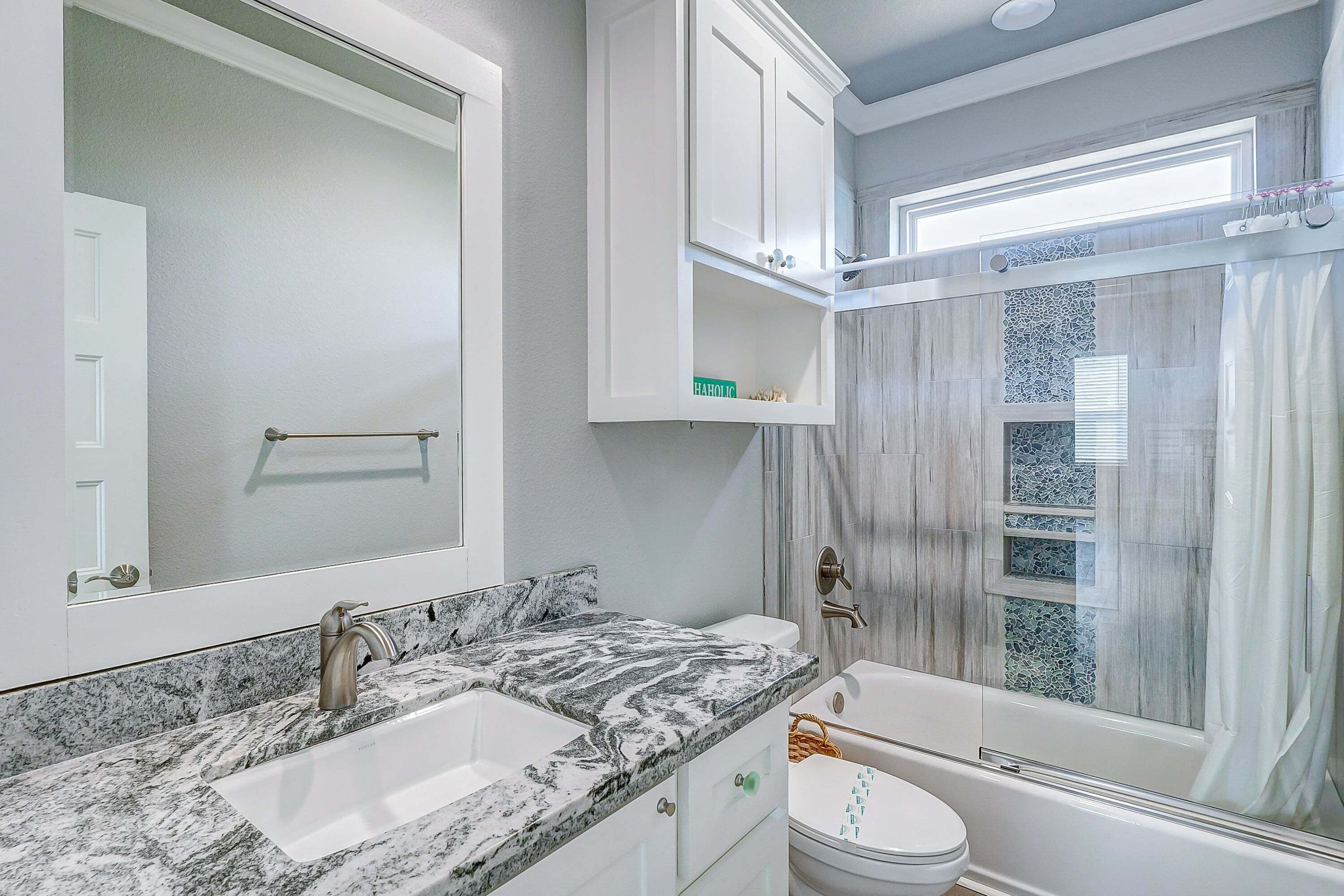 A bathroom with a marble countertop, a toilet, a bathtub, and a shower with a glass door.