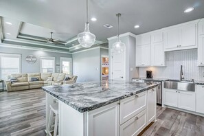 A modern kitchen with white cabinets, a marble countertop, and pendant lighting. - Hannah Cabana 3 Bedroom Home (Port Bolivar)