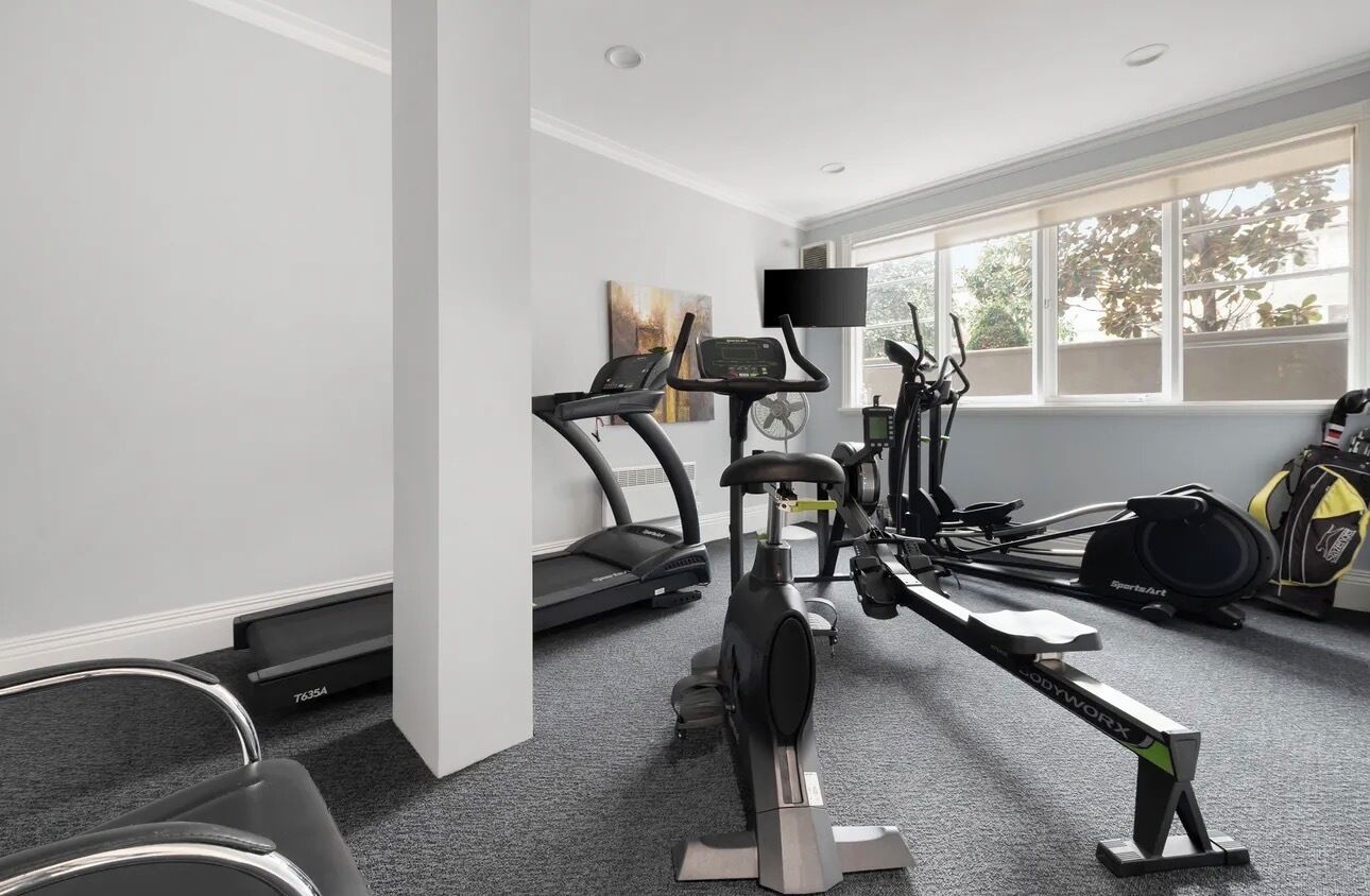 A gym with cardio machines, a TV, and a window with a view.