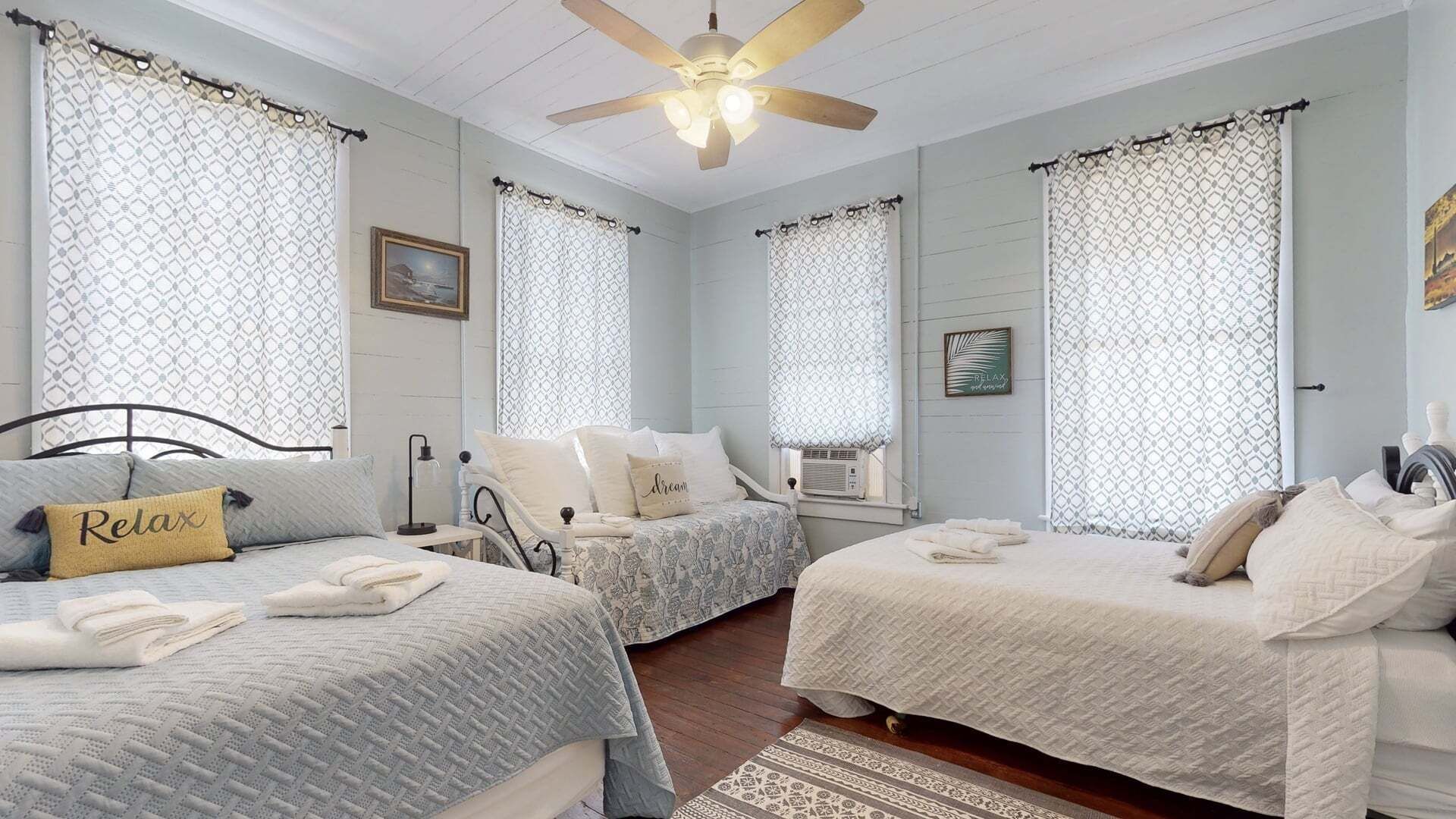 Un dormitorio con dos camas, un ventilador de techo y un cuadro en la pared.