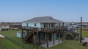 A two-story house with a wooden deck and a covered porch. - Casa Siwichi 2 Bedroom Home (Port Bolivar)