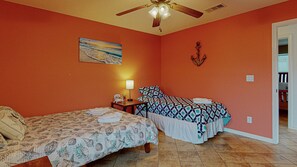 A room with two beds, a ceiling fan, a painting, and a small table with a lamp. - Casa Siwichi 2 Bedroom Home (Port Bolivar)