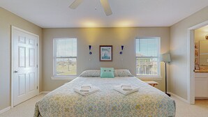 A bedroom with a bed, two windows, a ceiling fan, and a framed picture on the wall. - Sun And Moon 3 Bedroom Home (Port Bolivar)
