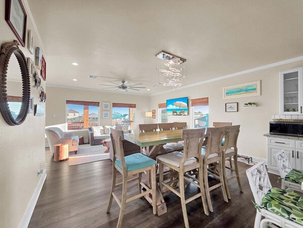 A dining area with wooden chairs and a table, a ceiling fan, and a view of the outside. - Do Hideaway 3 Bedroom Home (Port Bolivar)