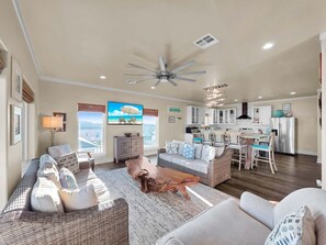 A spacious living area with a ceiling fan, a dining table, and a kitchen in the background. - Do Hideaway 3 Bedroom Home (Port Bolivar)