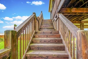 A wooden staircase leading to a building with a view of the ocean. - Sharkyfin's Ii 3 Bedroom Home (Port Bolivar)