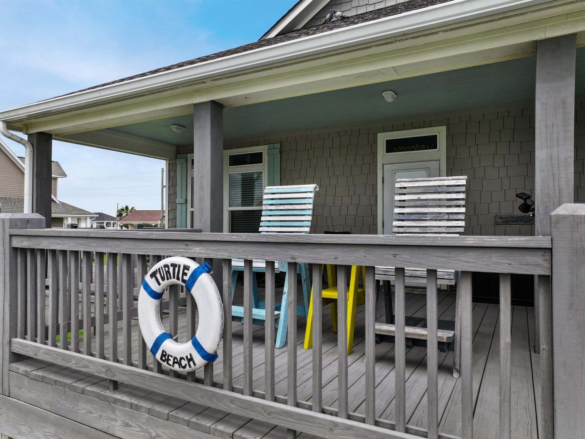A covered deck with a lifebuoy, a bench, and a chair.