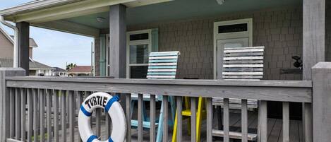A covered deck with a lifebuoy, a bench, and a chair.