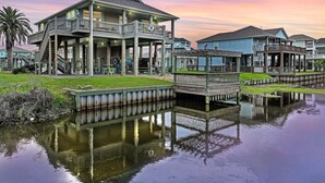 A waterfront property with a large house featuring multiple decks and a covered patio area. - Turtle Beach 3 Bedroom Home (Port Bolivar)