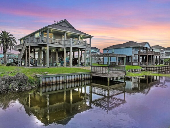A waterfront property with a large house featuring multiple decks and a covered patio area. - Turtle Beach 3 Bedroom Home (Port Bolivar)