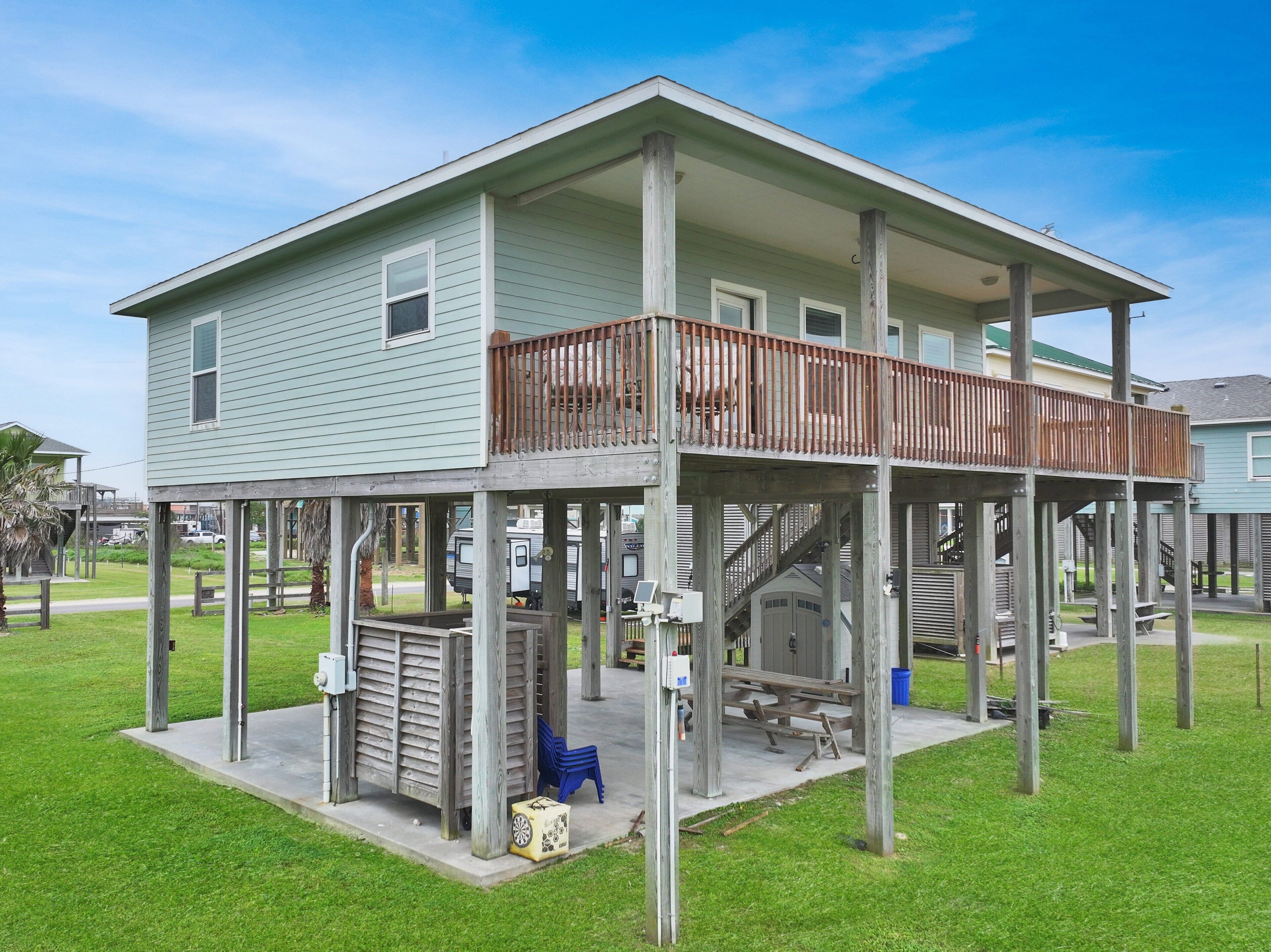 A two-story house with a balcony, a covered patio, and a small outdoor seating area.