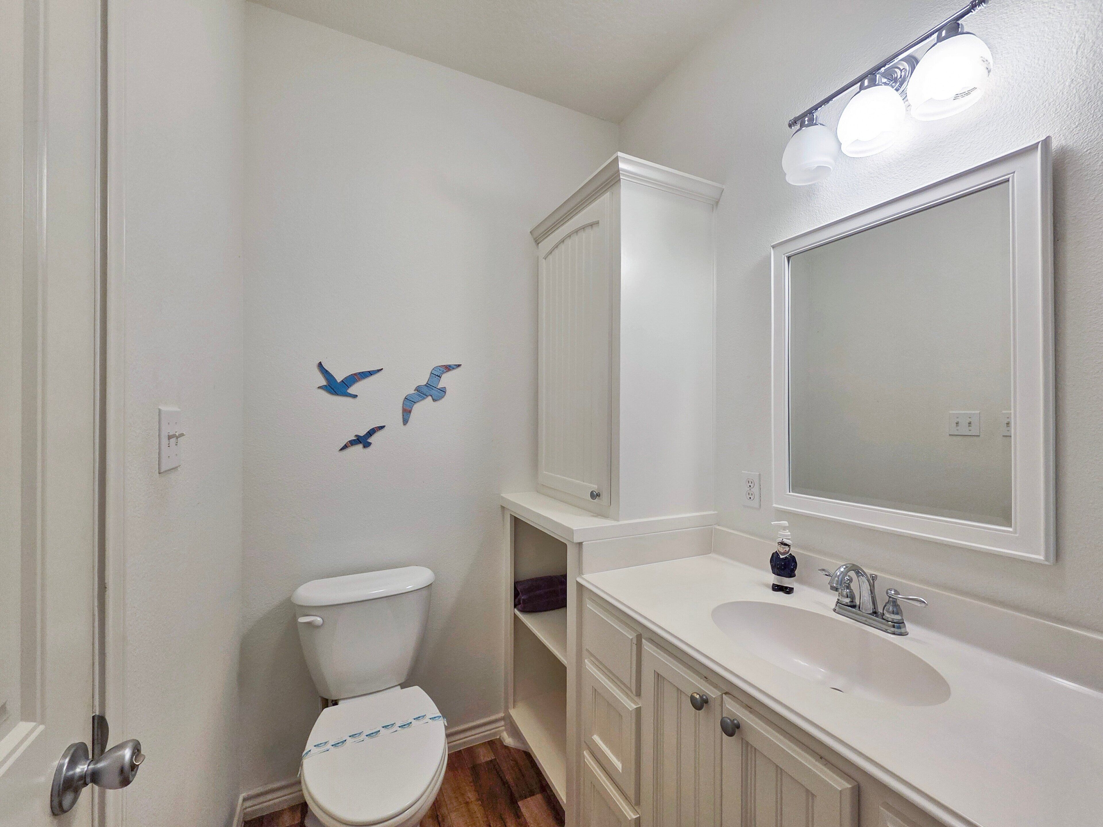 Een badkamer met toilet, wastafel, spiegel en wandlampen.