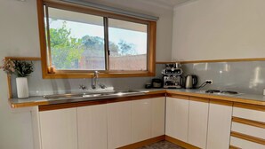 A kitchen with a window, a sink, a coffee maker, and cabinets.