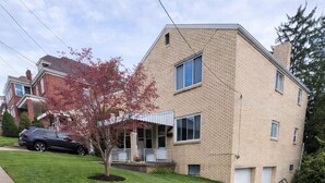 Ein Wohnhaus mit Backsteinfassade, einer Veranda und einem gepflegten Rasen.