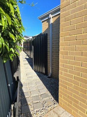 Un sendero que conduce a un edificio con fachada de ladrillo y valla metálica.