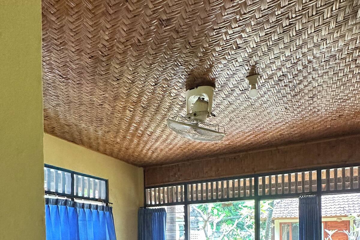 Ein Zimmer mit zwei Betten, einem Deckenventilator und einem Fenster mit blauen Vorhängen.