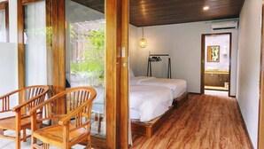 A bedroom with a bed, wooden floor, and a sliding glass door leading to a balcony. - Paradise Palm Beach Bungalows and Dive Center (Tulamben)