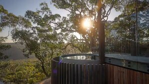 A modern outdoor area with a circular structure, surrounded by trees and a clear sky. - Patonga House: Stunning Views, Privacy, Heated Pool and Panoramic Outdoor Sauna (Patonga)