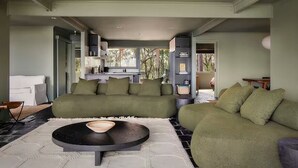 A modern living room with a sofa set, a coffee table, and a view to the outside. - Patonga House: Stunning Views, Privacy, Heated Pool and Panoramic Outdoor Sauna (Patonga)