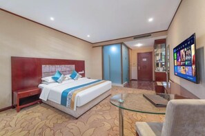 Una habitación de hotel con una cama grande, un escritorio, una silla y un televisor en la pared.