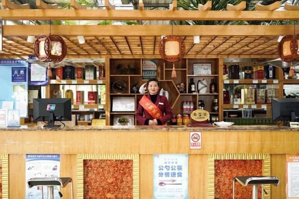 A reception desk with a wooden structure, various items on shelves, and a sign with text.