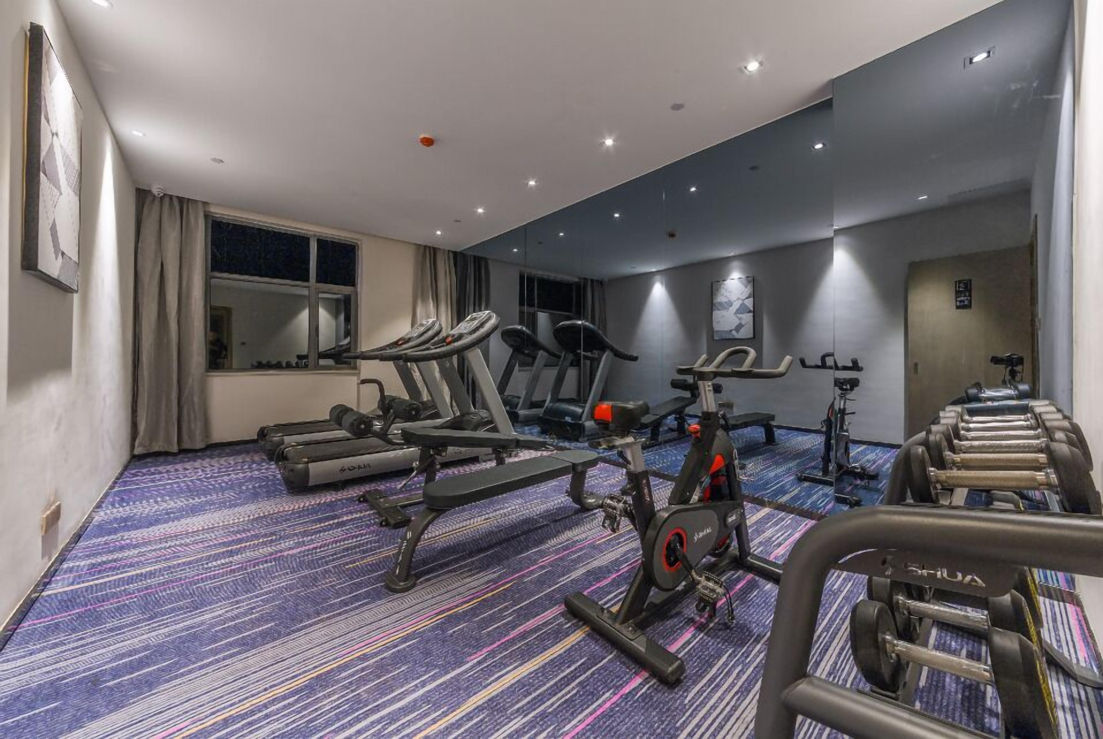 Een hotelgym met cardioapparatuur, gewichtbanken en haltersets.