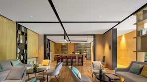 A modern living room with a central island bar, wooden flooring, and a herringbone-patterned wall. - Yishang Hotel Kunming Changshui Airport (Kunming)