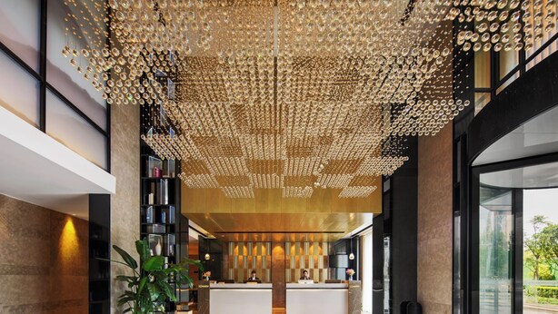 A modern hotel lobby with a reception desk, a large chandelier, and a view of the outdoors. - Yishang Hotel Kunming Changshui Airport (Kunming)