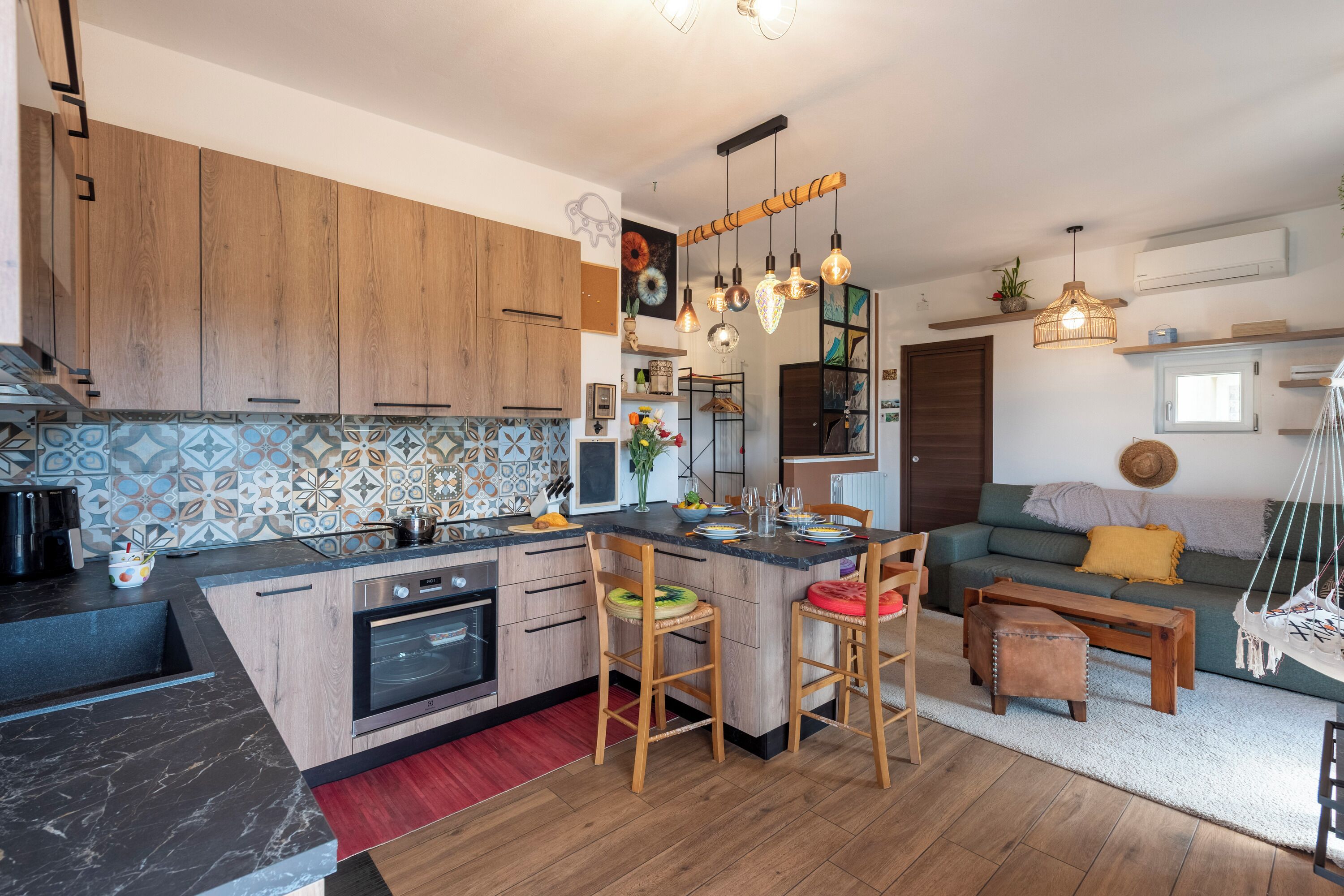 A modern kitchen with wooden cabinets, a central island, and hanging pendant lights.