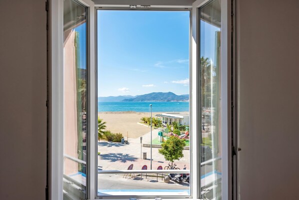 A view through a window of a beachside location with a clear sky, sandy beach, and distant mountains. - Da Lino Beachfront Apartment for 4, Sestri Levante, Italy (Sestri Levante)
