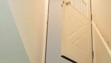 Un escalier dont les marches sont recouvertes de moquette, menant à une porte blanche dotée d’un panneau de verre.