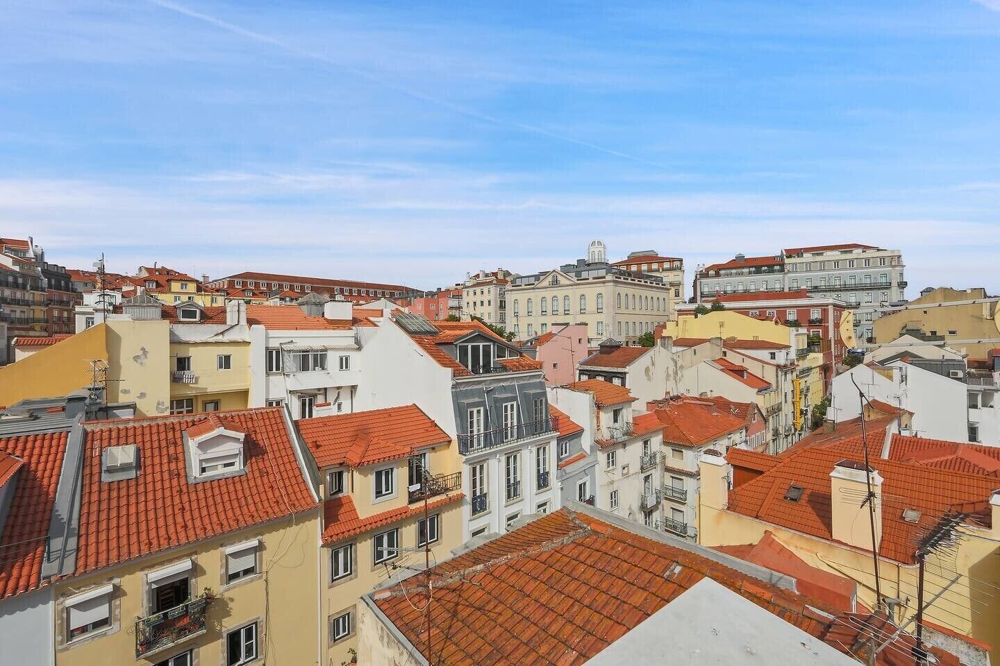 A densely packed urban area with various buildings, including multi-story structures with red-tiled roofs and balconies.
