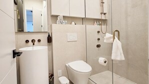 A modern bathroom with a toilet, sink, and shower.