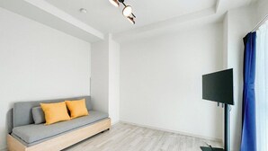 Ein schlicht eingerichteter Raum mit grauem Sofa, Flachbildfernseher und Holzboden.