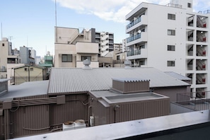Ein mehrgeschossiges Gebäude mit Balkonen, einer flachen Dachterrasse und sichtbarer Technik.