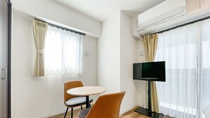 Ein Hotelzimmer mit einem runden Tisch, zwei Stühlen, einem Flachbildfernseher und einer Klimaanlage.