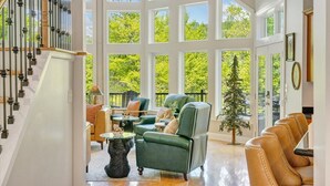 A spacious living room with a staircase, large windows, and leather furniture. - The Lakeside Lodge - 6BR Luxury Lakefront Property - Private Dock (Moneta)