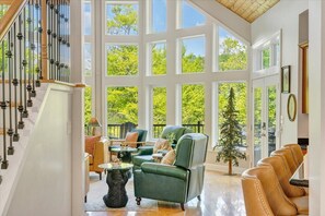 Ein geräumiges Wohnzimmer mit Wendeltreppe, großen Fenstern und Ledermöbeln.