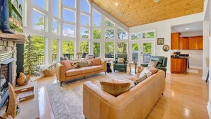 A spacious living room with a fireplace, large windows, and a high ceiling. - The Lakeside Lodge - 6BR Luxury Lakefront Property - Private Dock (Moneta)
