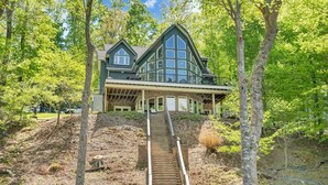 A two-story house with a covered porch and a staircase leading to the entrance. - The Lakeside Lodge - 6BR Luxury Lakefront Property - Private Dock (Moneta)